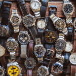 A large variety of watches are elegantly placed on a wooden table, emphasising their intricate designs and styles.